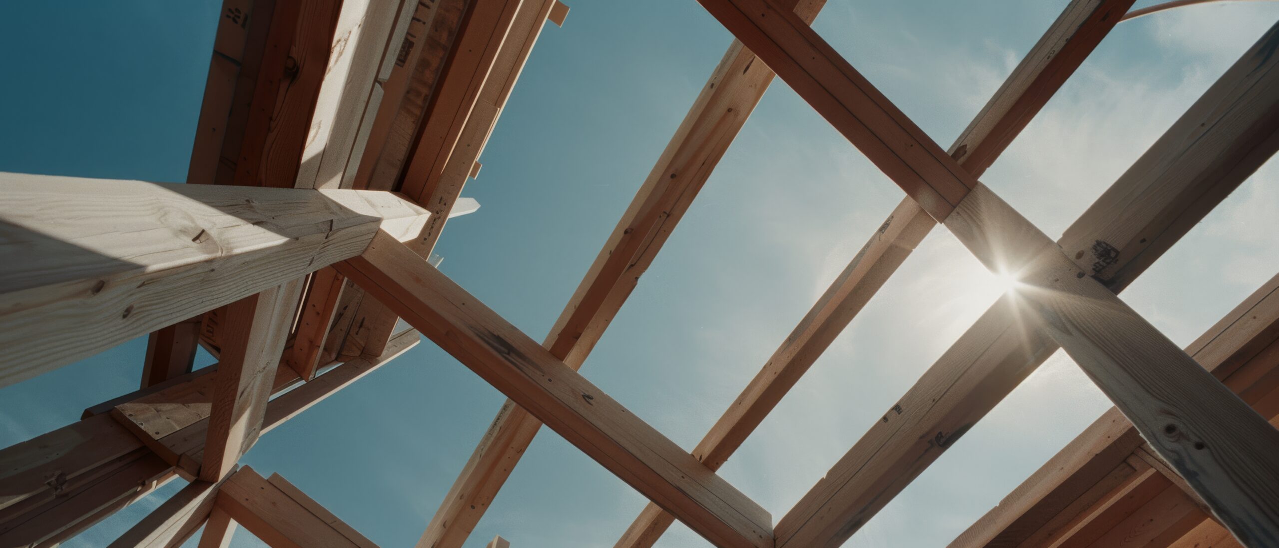 Sparren eines neuen Dachstuhls im Rohbau, von unten gegen den Himmel fotografiert